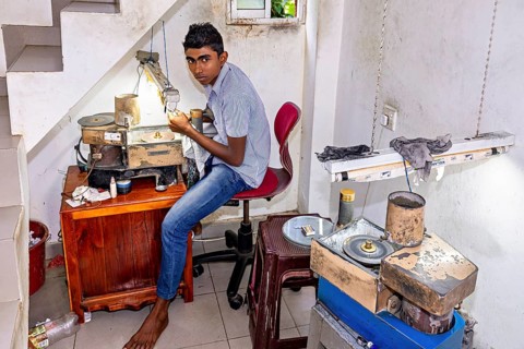 Young man working on a grinding machine in a small room with lighting, The gemstone cutters in the