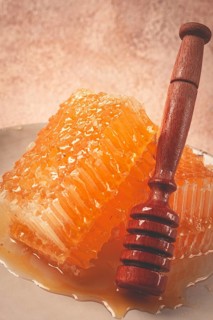 Honeycomb, with a wooden spoon-spindle, on a plate, no people