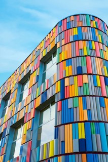 A modern building featuring a vibrant, multicolored, curved facade against a clear blue sky