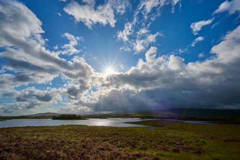 Wide natural landscape with sunbeams through clouds, river and green meadow, Rannoch Moor, Bridge