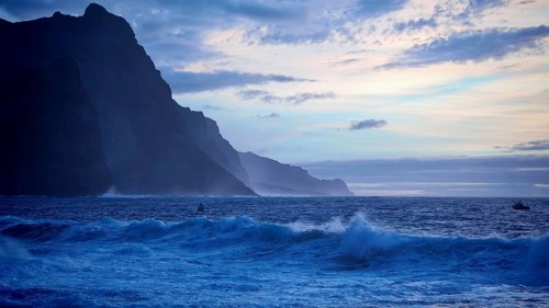 Evening at sea with cliffs, blue sky and waves in a cool atmosphere, dramatic silhouette of
