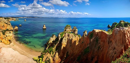 Panoramic view of a rocky coastal landscape, beach, lush green vegetation with clear blue sea and