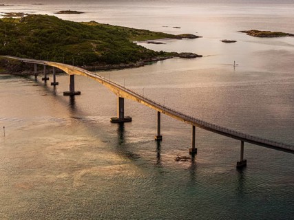 Sommaroy Bridge connecting Kvaloya Island to Sommaroy Island, warm light at sunset, aerial view,