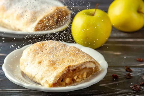 Ready apple strudel on a plate, sprinkled with powdered sugar