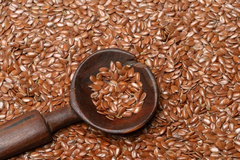 Linseed with wooden spoon, seeds of the common flax (Linum usitatissimum)