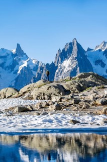 Young man in front of impressive mountain landscape in morning light, reflection in the Lac Blanc