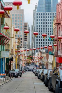 San francisco chinatown street with red lanterns strung above a steep, colorful historic block,