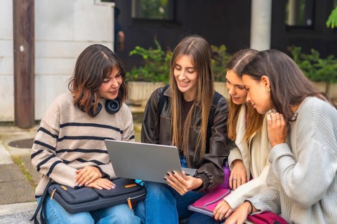 Group of happy female university friends collaborating on a project, learning and sharing knowledge