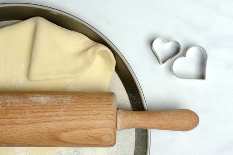Rolled dough on cake tray with dough rollers and cookie cutters