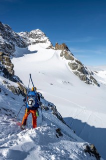 Mountaineer with skis at the fork Porta d'Es-cha, view of mountain peak Piz Kesch and glacier