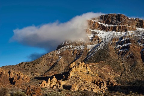 Rugged, snow-capped mountains with a few clouds against a clear sky, Teide National Park, Teide