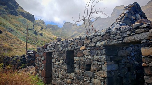 Ruined volcanic stone house in a mountainous landscape under cloudy sky, hiking, lost place,