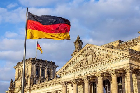 Reichstag building Berlin with German flags. Exterior view with dark clouds. Berlin, Germany