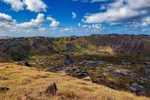 Far-reaching views of the crater and its surroundings under a blue, cloudy sky, Ranu Kau volcano on