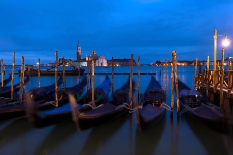 Nighttime atmosphere with moving gondolas, San Georgio Maggiore in the back, Guidecca Island on the