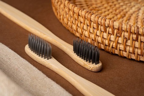 From above view showcasing bamboo toothbrushes with black bristles on a brown surface paired with a