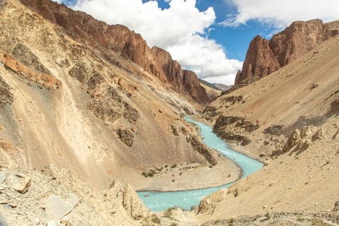 A stunning landscape of a turquoise river winding through rugged mountains in Ladakh. The arid