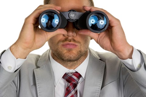 A manager (young entrepreneur) with binoculars looking for orders or jobs, studio shot