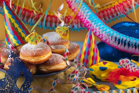 A plate of donuts surrounded by colorful party hats, streamers and garlands, carnival