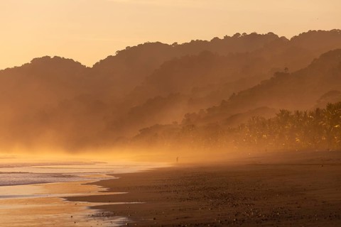 The low sun's golden light illuminates the ocean spray on Carate Beach, with views of Corcovado NP