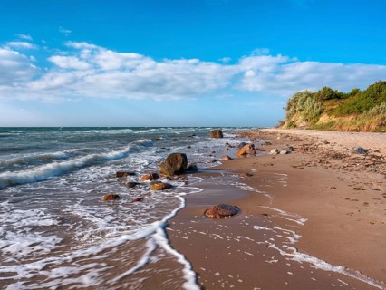 Unspoiled secluded stretch of coast with cliffs and boulders in the surf on the beach of the stormy