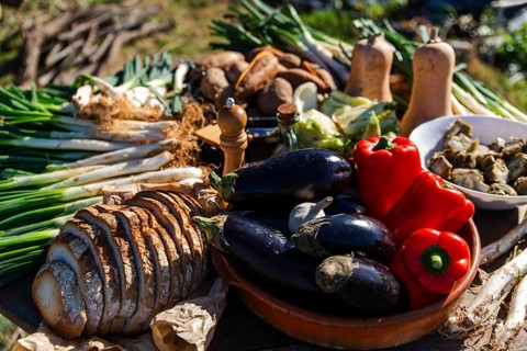 A colorful display of fresh calsots, vegetables, bread, and spices ready for a traditional Catalan