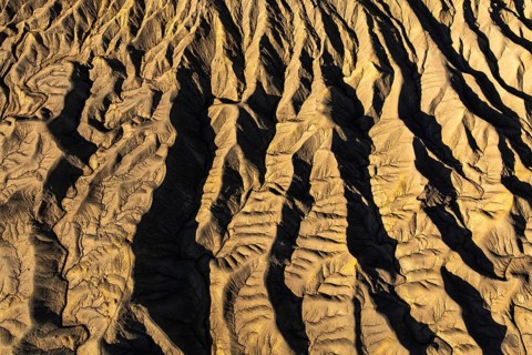 Aerial view of golden desert textures at Caineville Mesa, Utah. Features notable ridges and