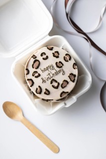 Top view of a South Korean bento cake with Happy Birthday icing in a white takeout box,