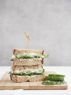 Cucumber and green spinach sandwich, cut in half and stacked, topped with a bamboo stick