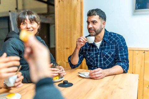 Friends sharing coffee and tea around a warm wooden table in a cozy urban cafe, smiling and