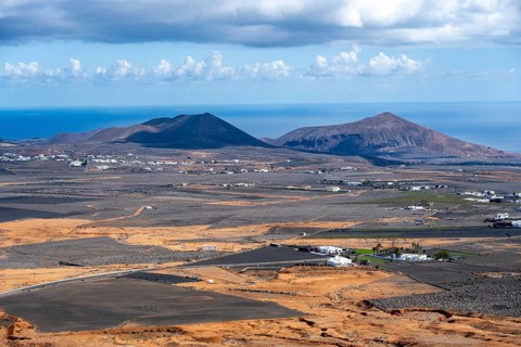 Dry volcanic landscape with houses and fields and volcanic craters, Lanzarote, Canary Islands,