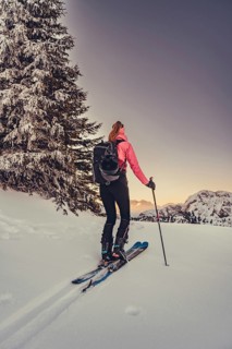 A woman's ski tour at sunrise on the Tegelberg in the Allgäu in the Ammergebirge, Bavaria, Germany