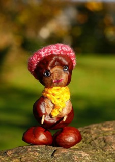 Funny chestnut figure with hat and scarf on a tree trunk, North Rhine-Westphalia, Germany