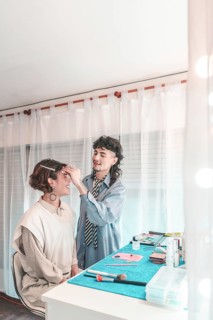 Professional makeup artist carefully applying makeup on a model's face, preparing her for a