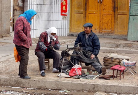 Xining, CHN, 27.02.09 - A woman puts on her repaired shoe at a shoemaker. A woman puts on a