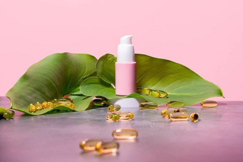 Elegant pink skincare dispenser with a white pump nozzle, framed by a lush green leaf and