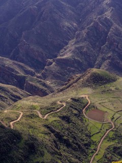Aerial view of a curvy road weaving through the lush, rugged terrain near Tejeda village on the