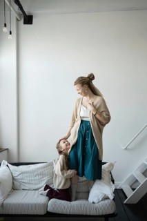 A mother and daughter share a joyful moment on a cozy couch The mother fondly looks down at her