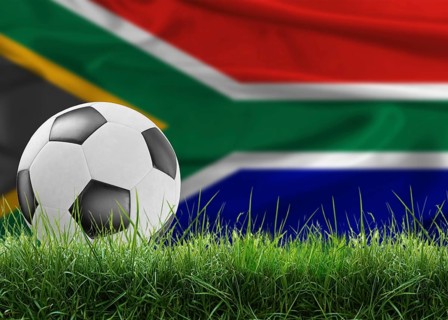 Soccer ball on pitch against South African flag in the background. Soccer ball on the grass with