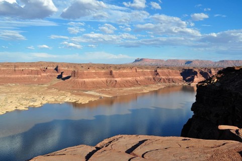 A lake in a vast canyon under clear skies surrounded by rocks and their shadows, Lake Powell,