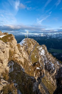 Mountaineer at the summit of the Kramerspitz with summit cross, at sunset, in autumn, Ammergau