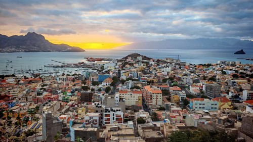 Panoramic view from above of coastal town of Mindelo at sunset with colorful buildings, harbor and