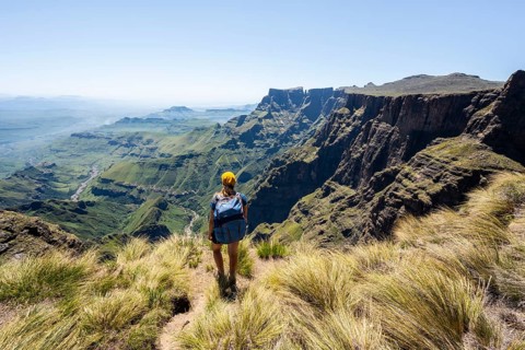 Young hiker looking at the impressive mountains and cliffs of the Drakensberg Mountains, hiking