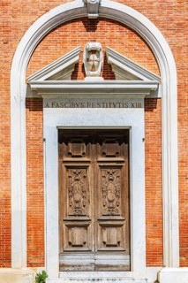 Decorated arched entrance gate in a brick façade, Pisa, Tuscany, Italy
