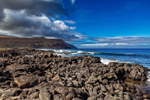 Rough rocky coast with dark clouds over a deep blue sea, the landscape of Easter Island in the