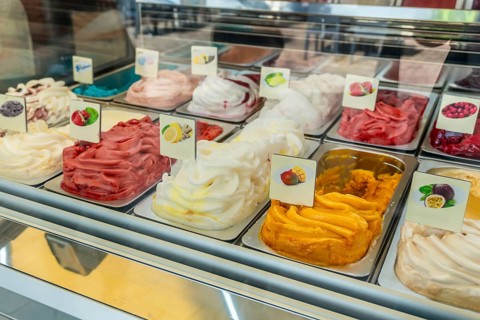 Display case showcasing a vibrant array of artisan ice cream and sorbet flavors, featuring fresh