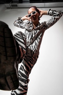 Model poses confidently in animal print attire, captured with dramatic flash photography in a