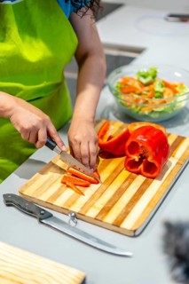 Vertical close-up of the hands of a latin young woman chopping vegetables while streaming online