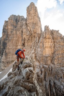 Mountaineer climbs on an exposed rock in the secured Via Ferrata Bocciere Centrale via ferrata,