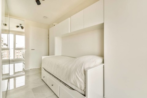 Modern minimalist bedroom with a loft bed and built-in storage, featuring clean lines, white